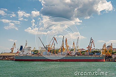 Cranes load cargo from the ship in the seaport Stock Photo