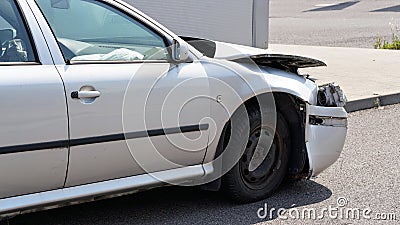 Crashed car standing on road next to curb, side view with demolished front and used airbag inside visible Stock Photo