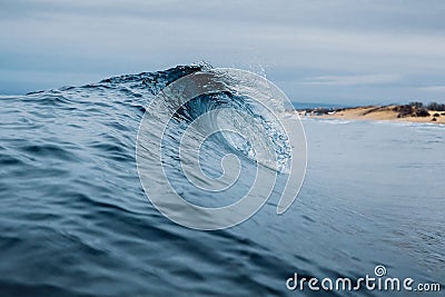 Crashing glassy wave on the sandy beach. Breaking ocean wave, ideal swell for surfing Stock Photo