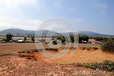 Crater from exploded cluster bomb near to village and mountains in Xieng Khouang Province, Laos. Stock Photo