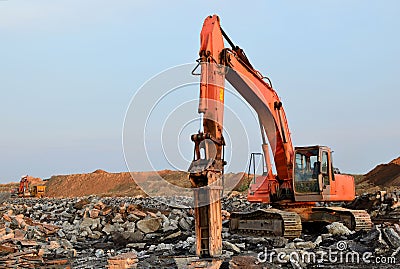 Crawler excavator with hydraulic hammer for the destruction of concrete and hard rock at the construction site. Salvaging and Stock Photo