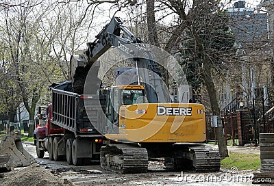 A crawler excavator loads dirt onto a dump truck in Chicago Editorial Stock Photo