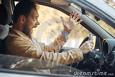 Crazy Angry Man Annoyed While Driving a Car. Mad Agrressive Driver Screaming Irritated with Traffic Stock Photo