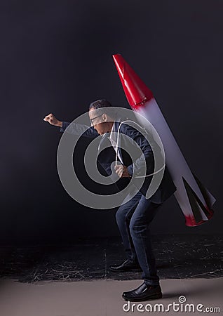 Crazy business man carrying missile weapon standing in dark stud Stock Photo