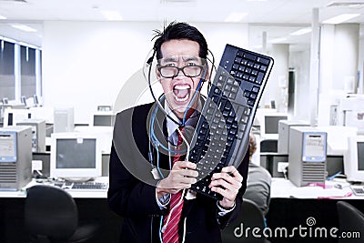 Crazy businessman hold keyboard at office Stock Photo
