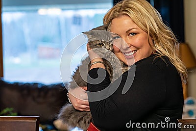 Crazy cat woman blonde girl cuddles with a grey barn kitten Stock Photo