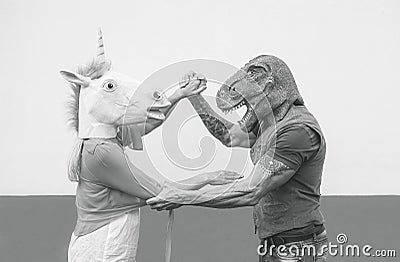 Crazy couple dancing and wearing dinosaur and unicorn mask - Senior trendy people having fun masked at carnival parade Stock Photo