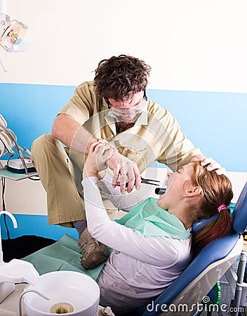 Crazy dentist treats teeth of the unfortunate patient. The patient is terrified. Stock Photo