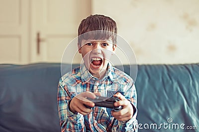 Crazy dependent kid shouting while playing video game Stock Photo