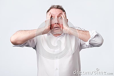 Crazy desperate senior man being shocked looking at camera trembling with fear. Stock Photo