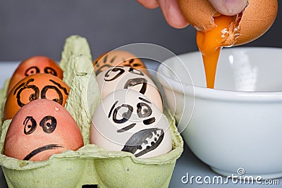 Crazy eggs terrified, Scared faces staring from egg tray at broken egg. Funny easter stories. Stock Photo