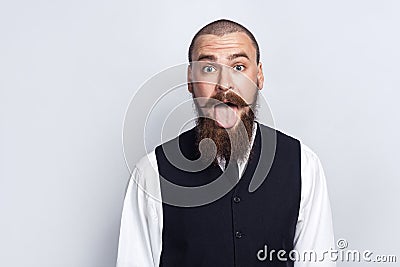 Crazy Funny face. Handsome businessman with beard and handlebar mustache looking at camera with tongue out. Stock Photo