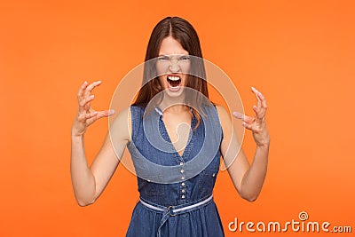 Crazy mad brunette woman in denim dress screaming angrily with furious enraged expression Stock Photo