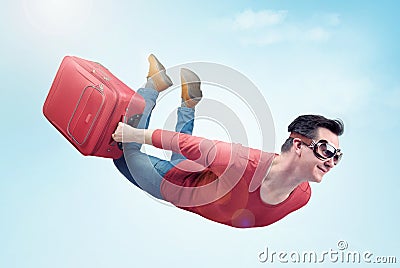 Crazy man in goggles and with red suitcase flies in the sky. Concept of vacation Stock Photo