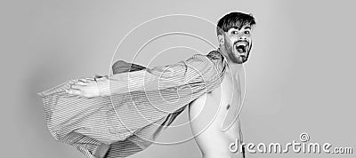 Crazy man posing with naked sexy torso in white pants and flying open robe on grey background. Stock Photo