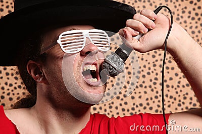 Crazy rock and roller singer with a big black hat, party glasses in front of a cheetah skin background Stock Photo