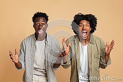 Two Excited Happy Black Guys Raising Hands And Opening Mouth In Amazement Stock Photo