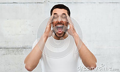 Crazy shouting man in t-shirt over gray wall Stock Photo