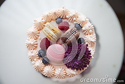 Cream cake seen from above, with macarons, blueberries, raspberries, purple flower and pearls Stock Photo