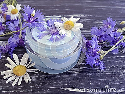 cream cosmetic flowers cornflower, camomile on a dark wooden background Stock Photo