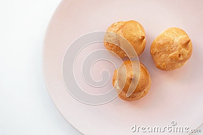 Cream puff cakes, close-up. Portion of dessert in pink dish on white background with selective focus. French pastry Stock Photo