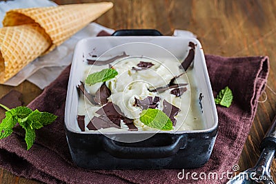 Creamy mint ice cream with chocolate chips in a black ceramic mold on a brown wooden background. Ice cream recipes Stock Photo