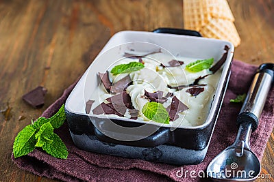 Creamy mint ice cream with chocolate chips in a black ceramic mold on a brown wooden background. Ice cream recipes Stock Photo