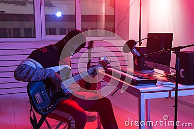 Create music and a recording studio concept - Black man guitarist recording electric bass guitar track in home studio Stock Photo