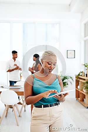Creating great designs doesnt always need a desk. a young businesswoman using a digital tablet in a modern office. Stock Photo