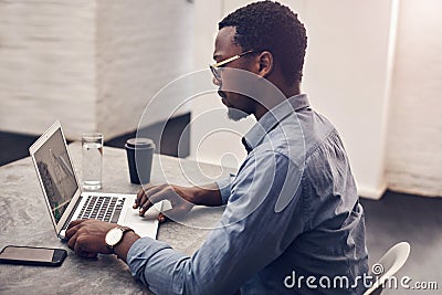 Creating some designs. a handsome young male architect working on a laptop in a modern office. Stock Photo