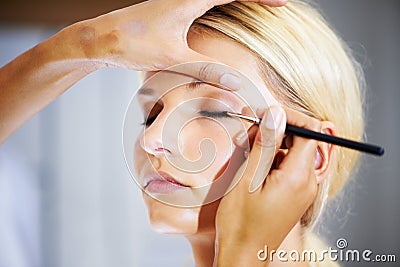 Creating a versatile make-up look. Pretty young woman having her makeup applied by a stylist. Stock Photo