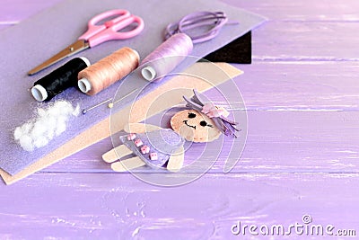 Creative art and craft idea for children. Felt doll, scissors, thread, needles, pins, suede cord, felt sheets on wooden background Stock Photo