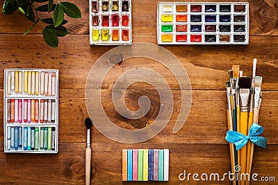 Creative art work accessories tools supplies items set concept, paint brushes, paintbox with watercolors, crayons on brown wooden Stock Photo