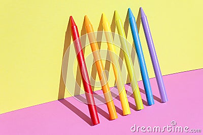 Creative back to school concept. Multiple colorful wax crayons isolated on the pink and yellow color background. Stock Photo