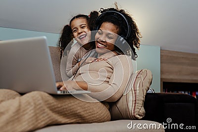 Creative black mother and daughter working on school project, using modern laptop Stock Photo