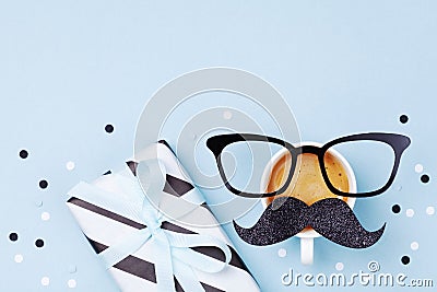 Creative breakfast on Happy Fathers Day with gift box and funny face from cup of coffee, eyeglasses and moustache. Flat lay Stock Photo
