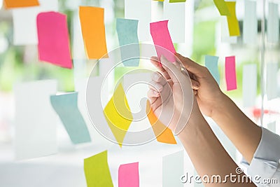 Creative business people reading sticky notes on glass wall with Stock Photo