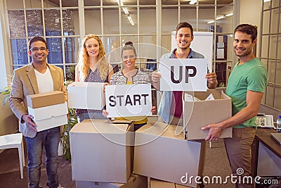 Creative business team holding cardboard written start up Stock Photo