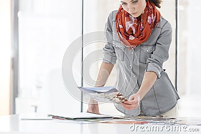 Creative businesswoman reviewing photographs at desk Stock Photo