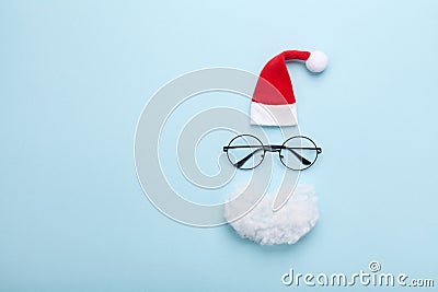 Creative christmas composition. Greeting card, invitation or flyer. Santa hat, beard and glasses on blue background top view. Stock Photo