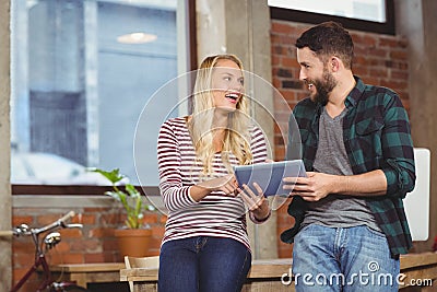 Creative colleagues smiling while discussing over tablet Stock Photo