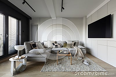 Creative composition of living room interior with modern gray sofa, wooden coffee table, structual carpet, patterned pillows, Stock Photo