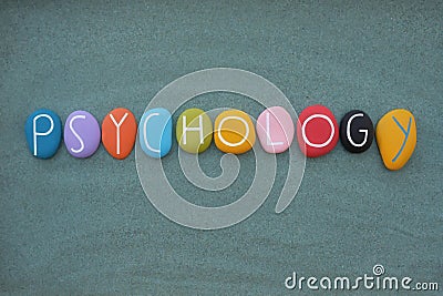 Psychology text composed with multicolored stone letters over green sand Stock Photo