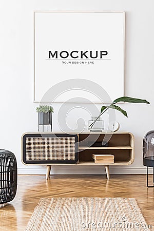 Creative composition of stylish living room interior design with mock up poster frame, wooden commode, leaves. Stock Photo
