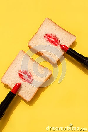 Creative concept made with red lipstick and lips on bread on bright yellow background. Minimal abstract composition Stock Photo