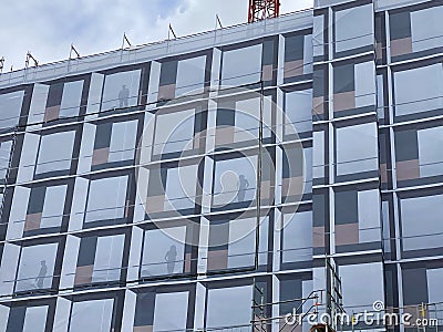 Creative decoration and cladding hanging on the scaffolding of modern building under construction. Stock Photo