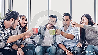 Creative designer take coffee break and toasting coffee cup at office cafeteria. multiethnics employee sitting at sofa and talking Stock Photo