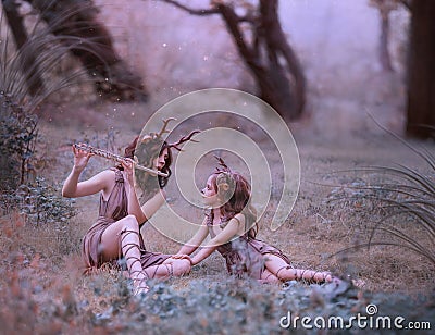 Creative fabulous family shooting, faun mom plays lullaby on flute for her child, fairytale characters deer in long Stock Photo