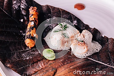 Creative Fine Dining: Fish topping with culinary foam serves with pea and grilled root with salt on torched leaf Stock Photo