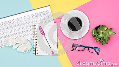 Top view office desk with notepad, wireless keyboard, succulent plant, coffee cup and glasses on pastel colored background. Stock Photo